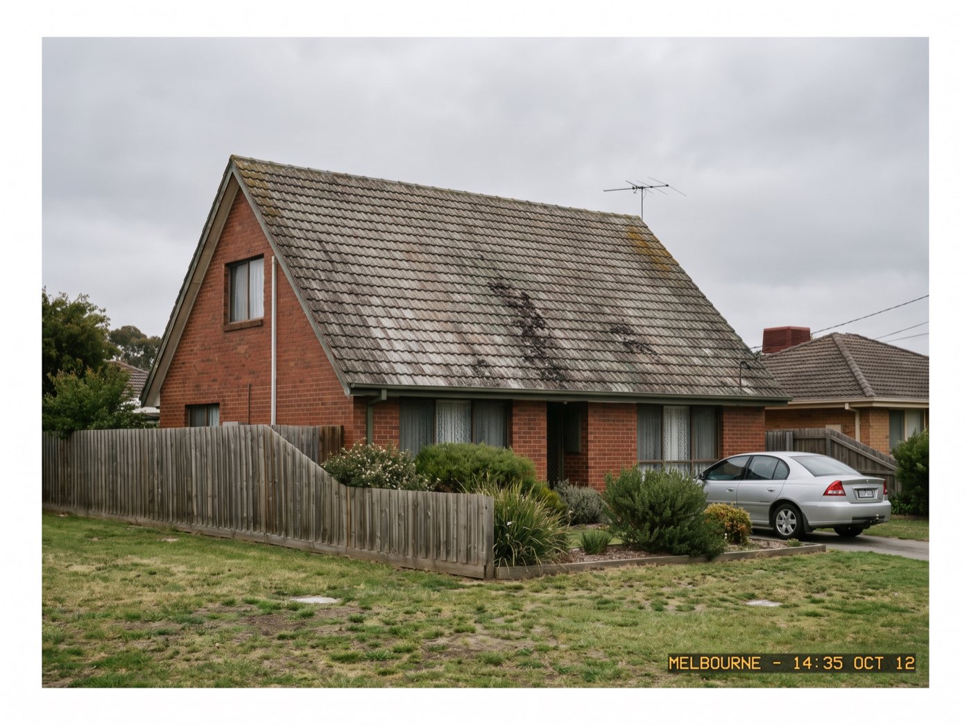 A faded patchy cement tile roof streaked with algae