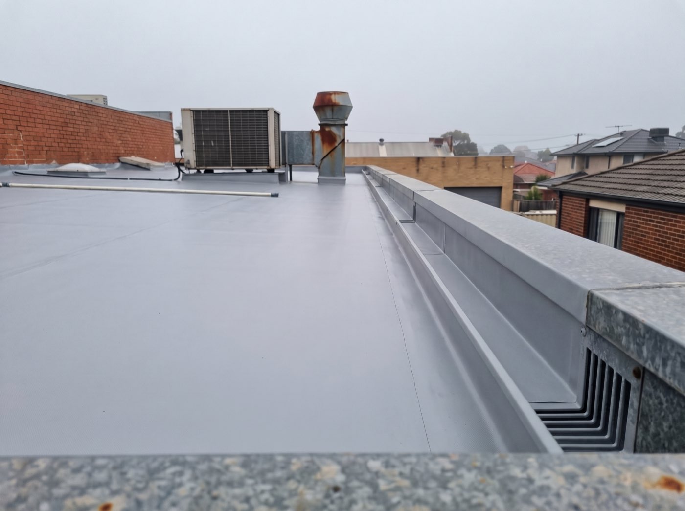 The same flat roof with a fresh seamless membrane and a clean box gutter