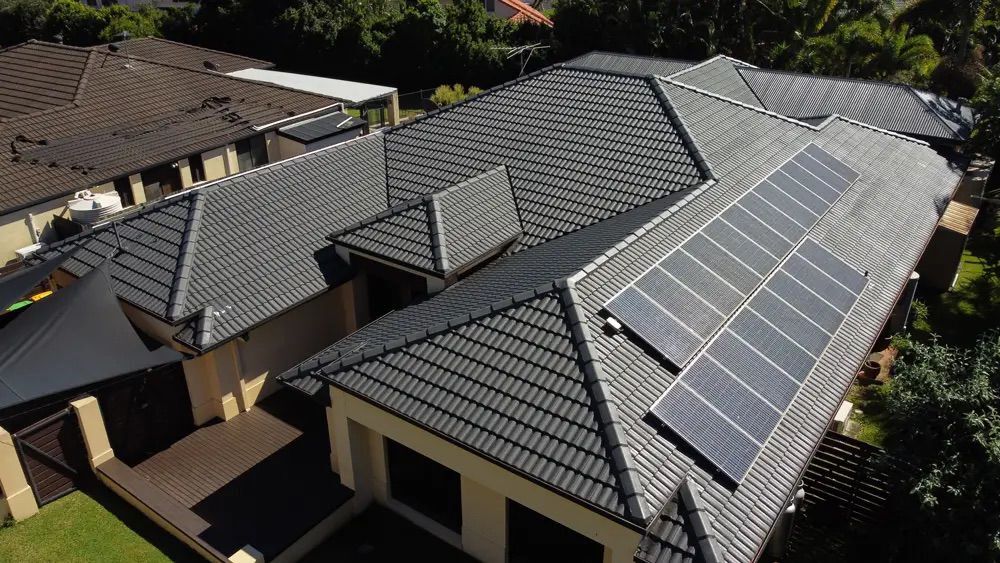 A finished charcoal tile roof restoration with solar panels on the roof