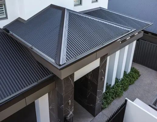 A dark metal roof over the entry of a new home