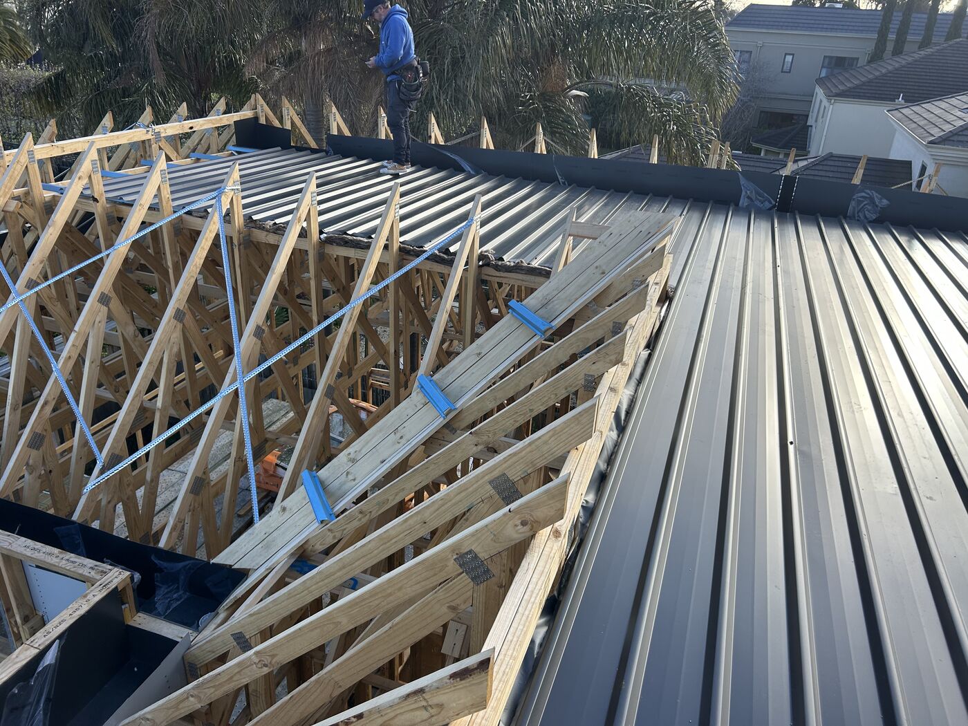 New timber roof trusses with metal roof sheets going on