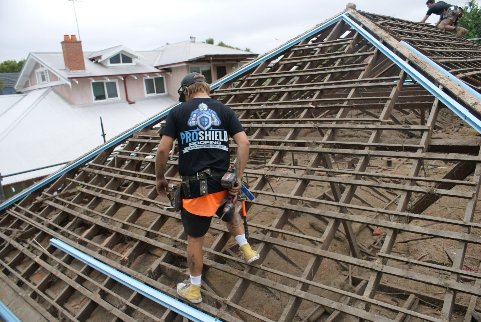 A Pro Shield roofer on a roof stripped back to the battens