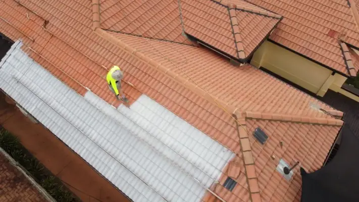 A roofer priming a terracotta tile roof