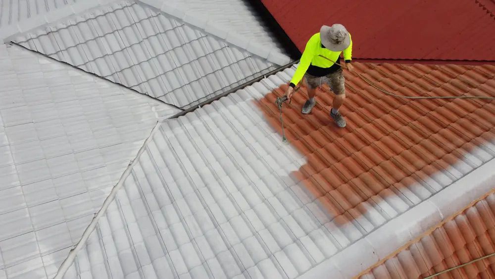 A roofer priming a terracotta tile roof, seen from a drone