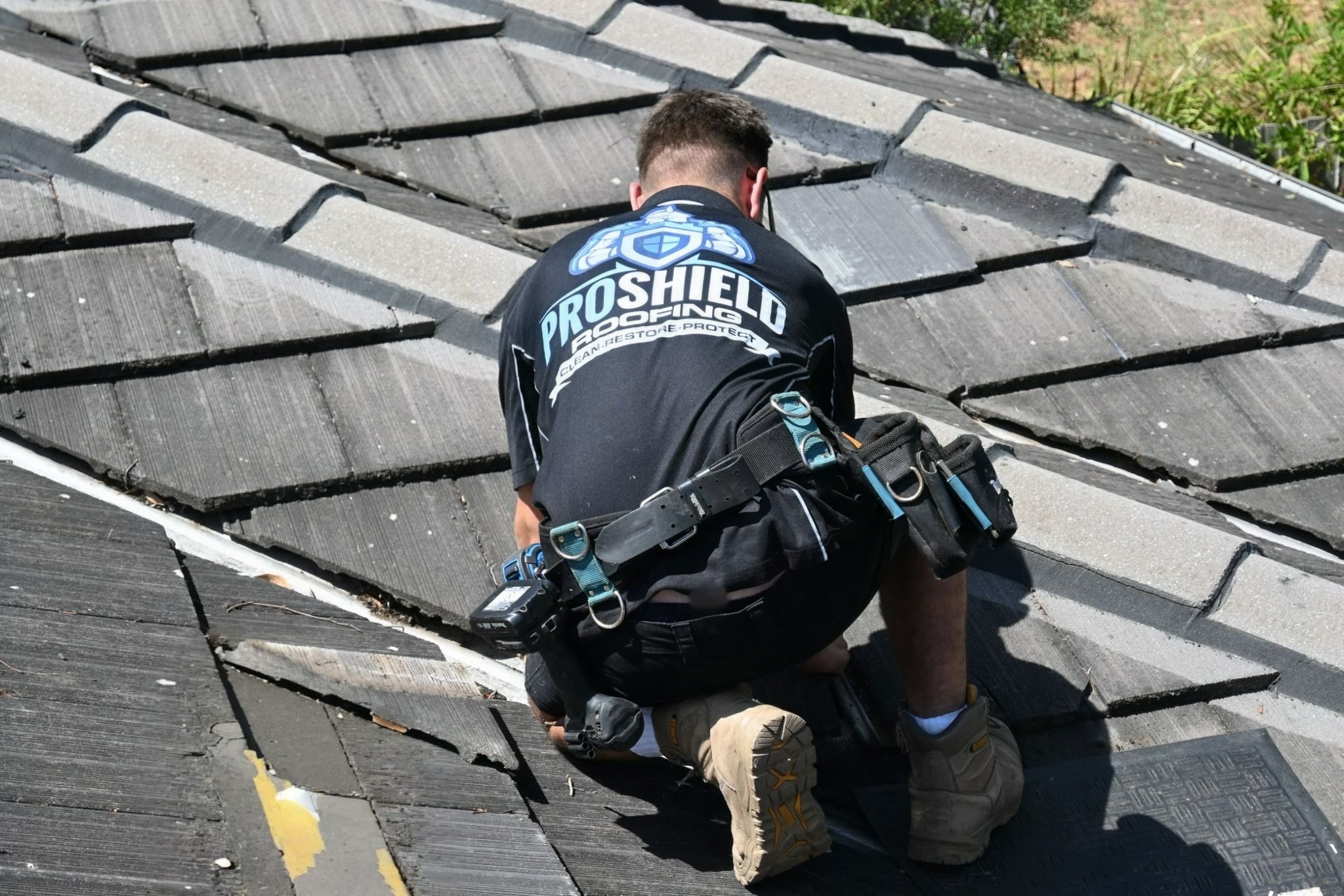 A Pro Shield roofer checking tiles beside a roof valley