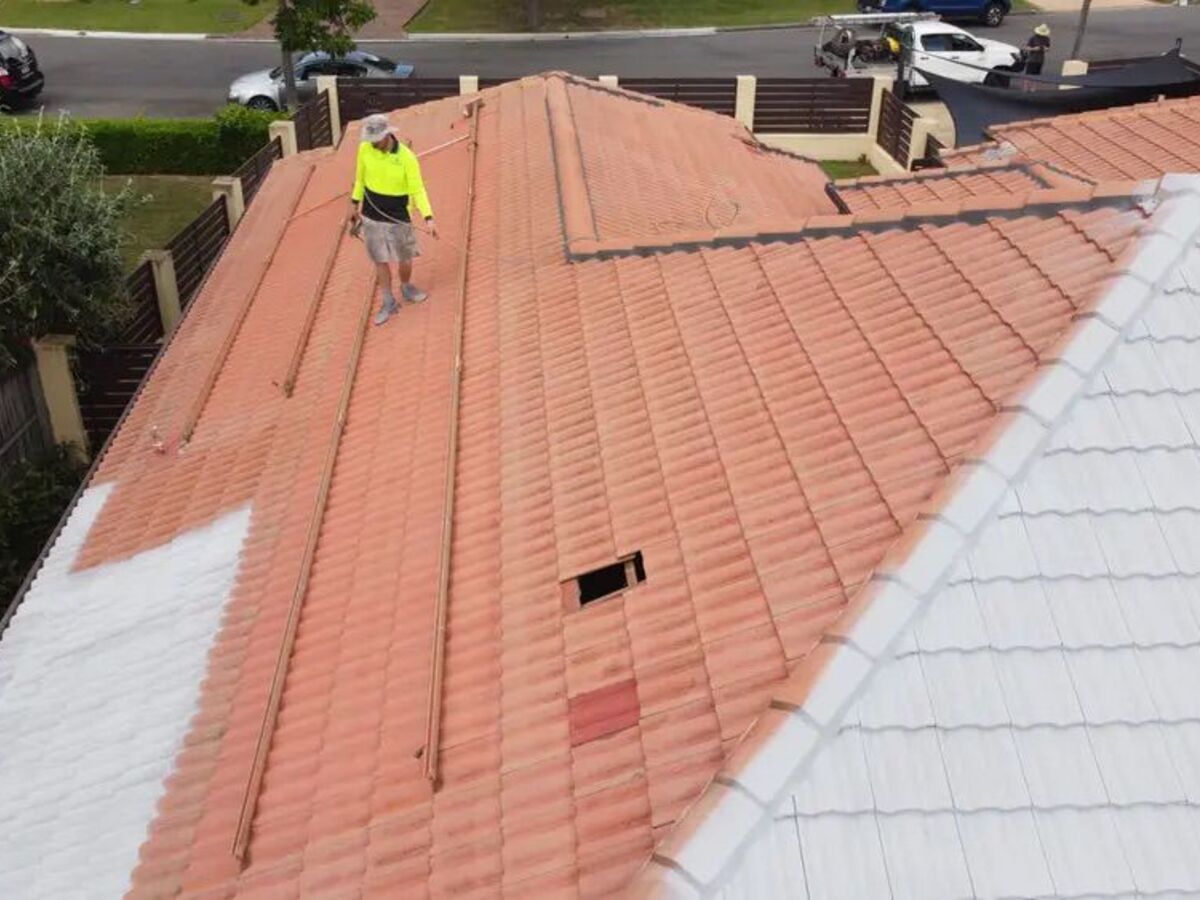 A terracotta tile roof part way through priming