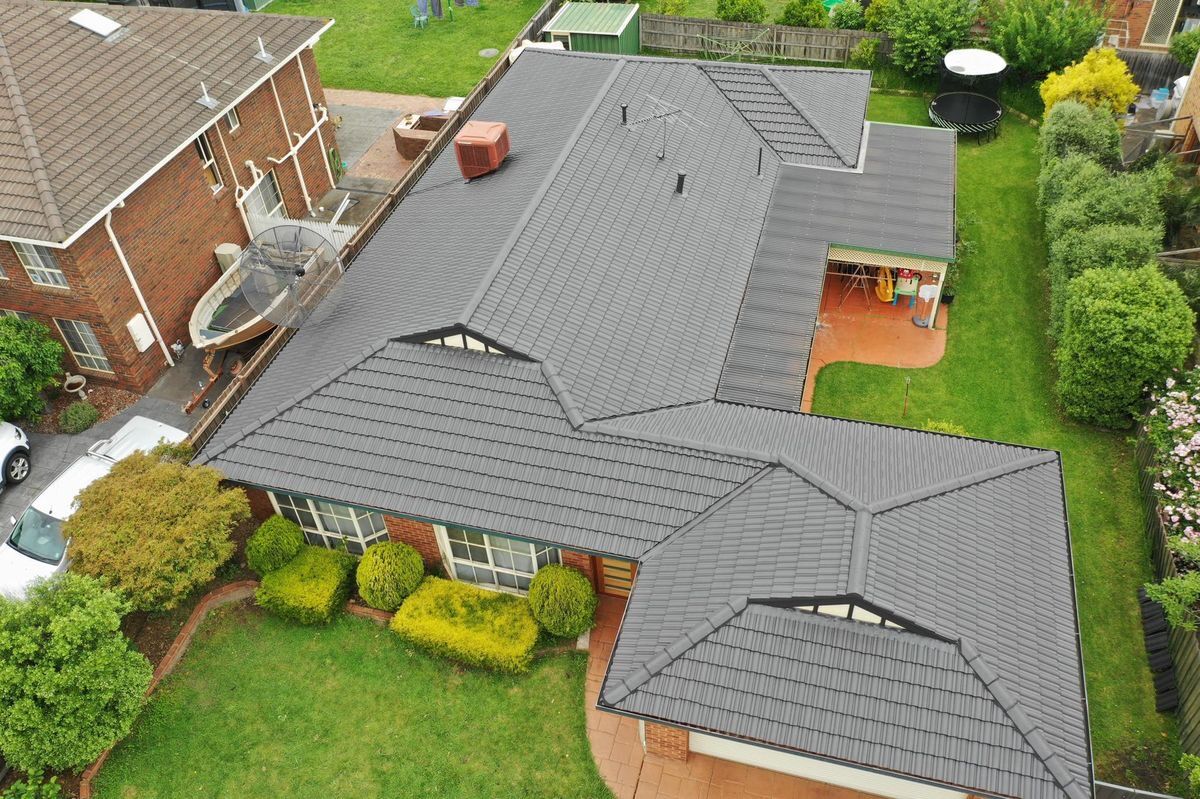 Drone photo of a finished charcoal tile roof restoration on a brick home